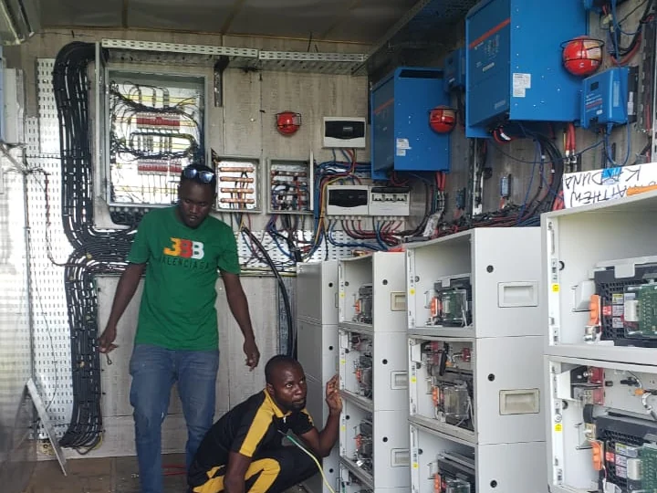 Alzaks engineers commissioning a containerised power room lined with inverters and racked battery cabinets