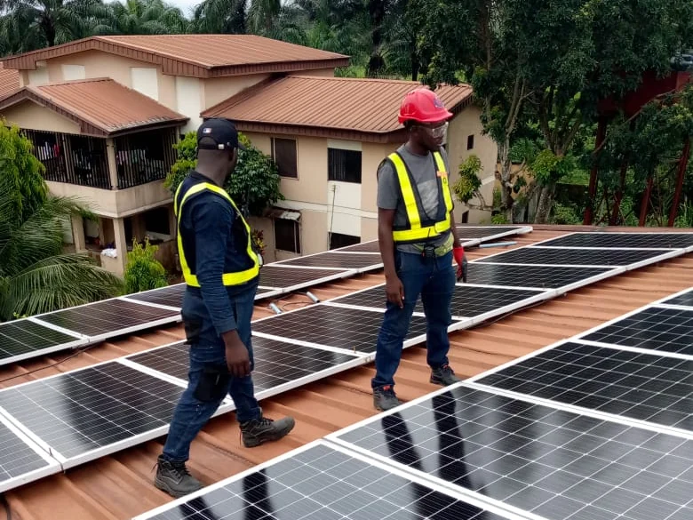 Two Alzaks technicians in hi-vis vests inspecting a completed rooftop solar array at a private residence